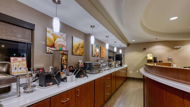 A hotel reception area with a long counter, wooden cabinets, and various amenities like a coffee machine and a food display. - Comfort Inn Shepherdsville - Louisville South (Louisville)