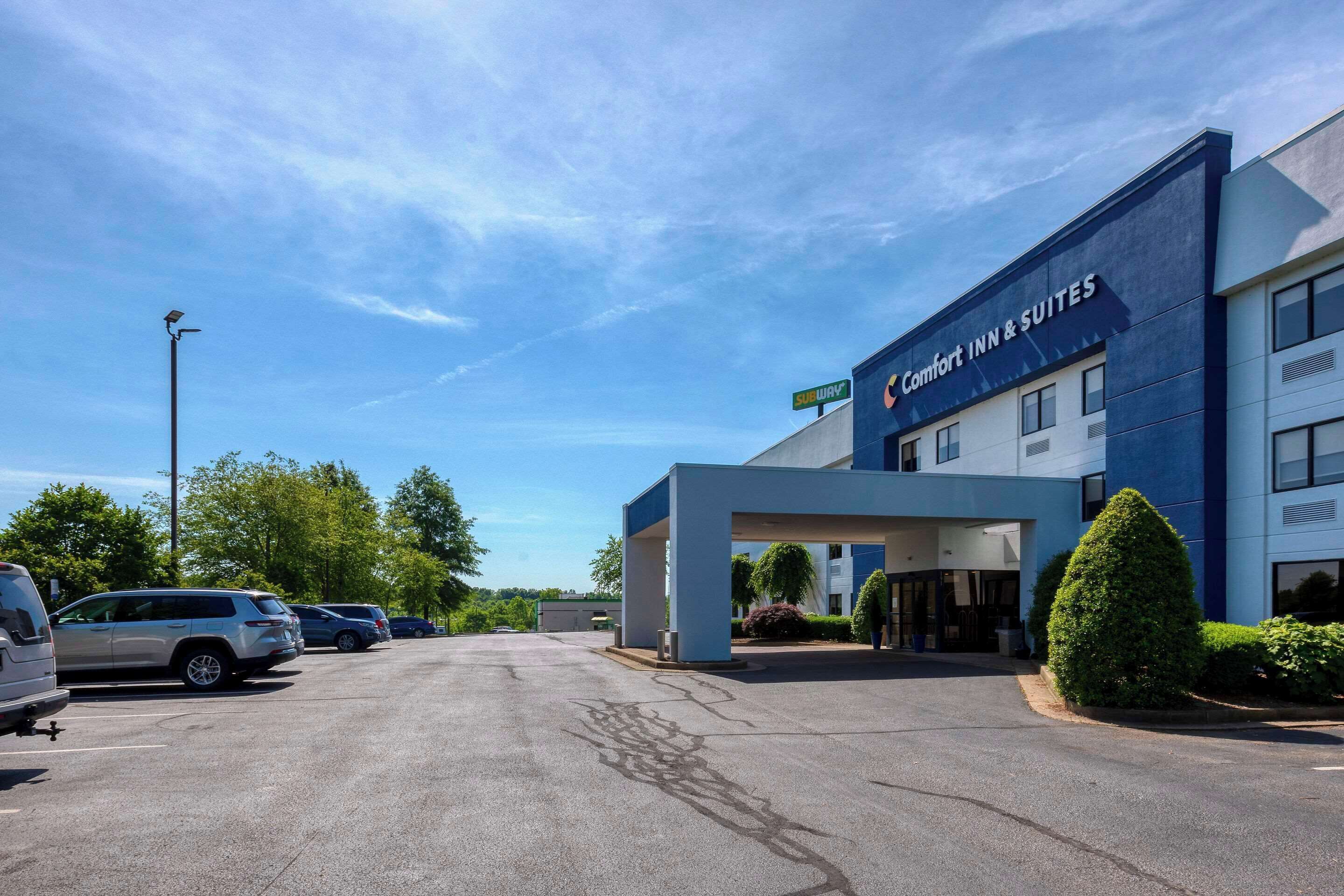 A Comfort Inn & Suites building with a modern design, a parking lot, and a clear sky.