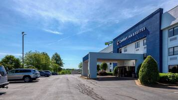 A Comfort Inn & Suites building with a modern design, a parking lot, and a clear sky.