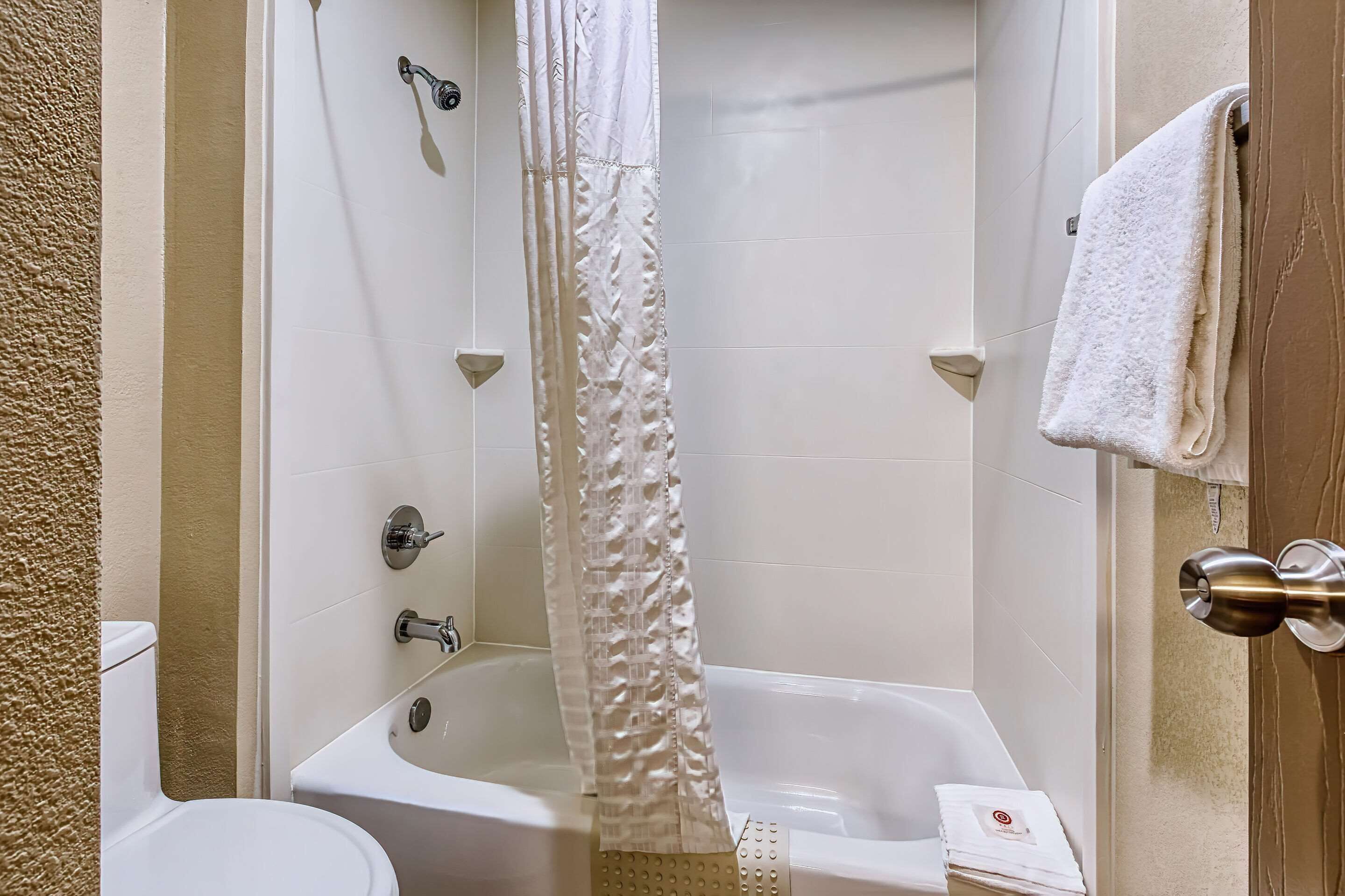 Un baño con bañera, inodoro y cortina de ducha.