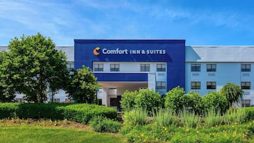Un hotel Comfort Inn & Suites con fachada moderna, múltiples ventanas y un jardín bien cuidado al frente.