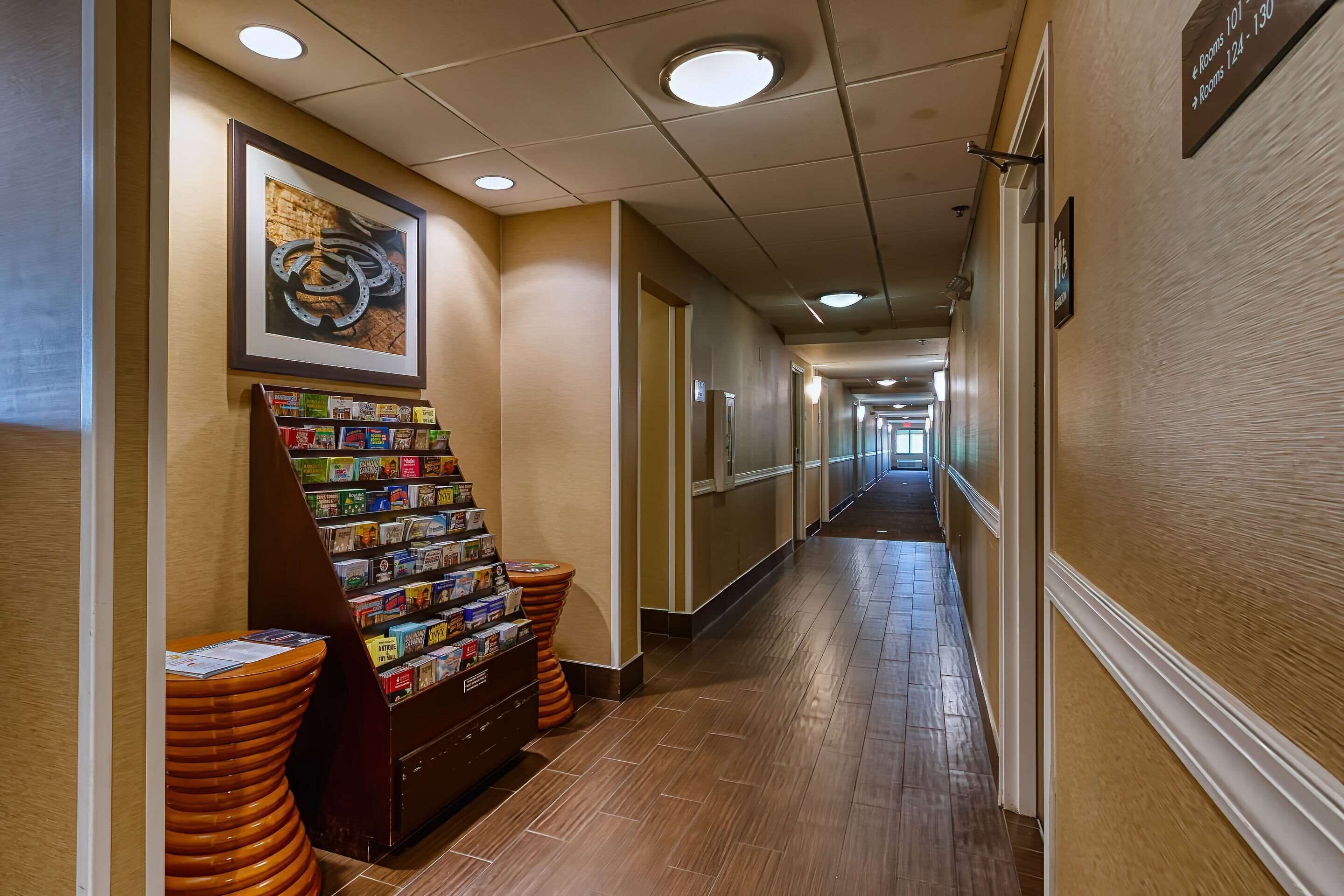 En hotellkorridor med en receptionsdisk, inramade konstverk och en informationsbroschyr.