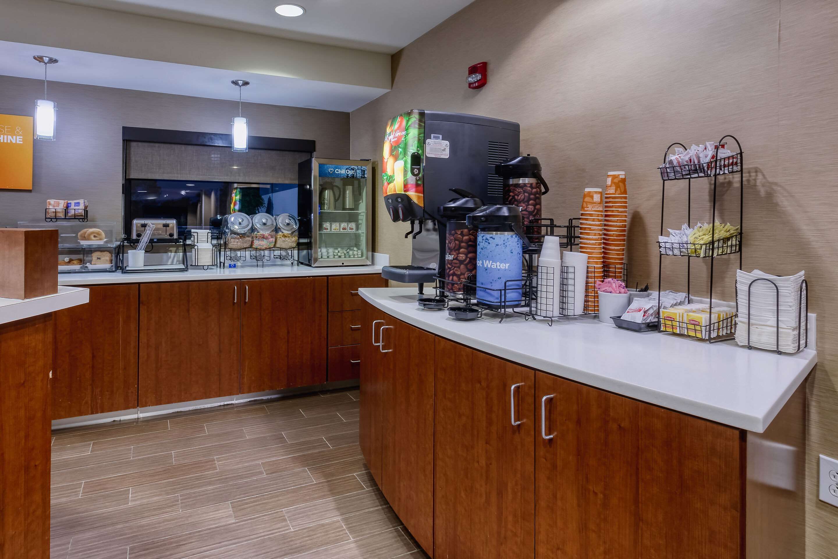 Een hotel receptie met een koffiehoek, een koelkast en een waterdispenser.
