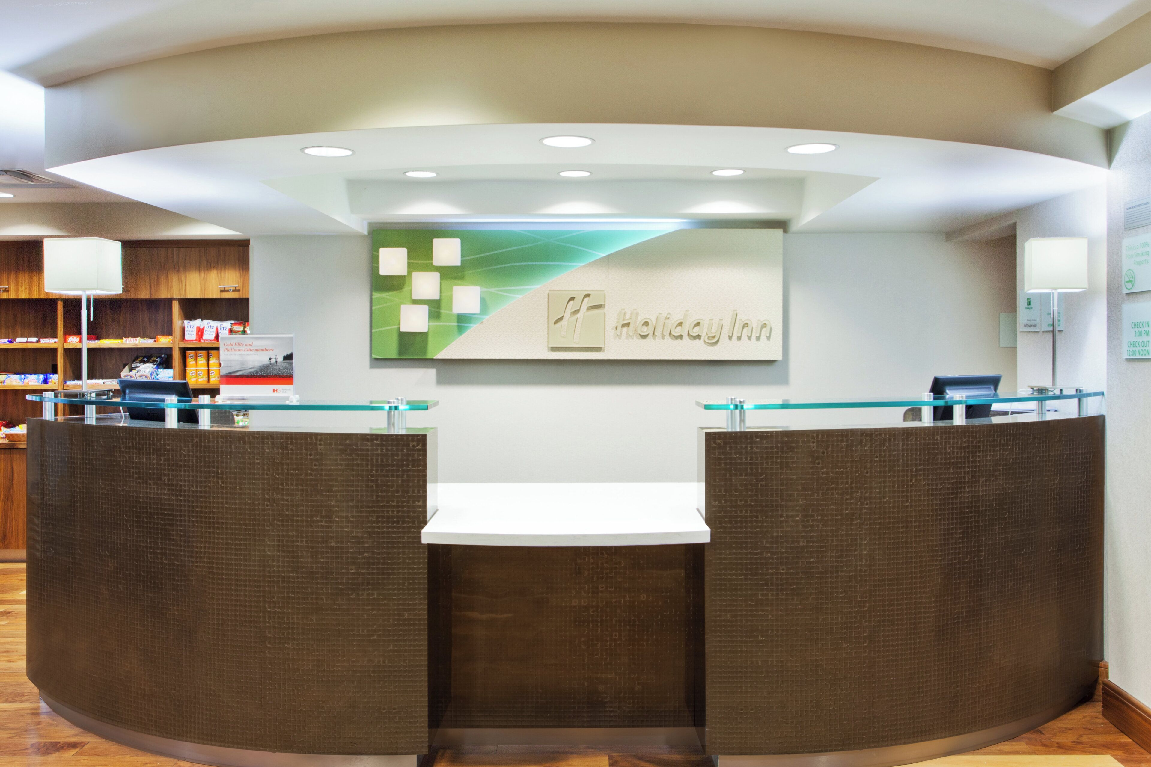 A reception area with a modern design, featuring a reception desk, a counter, and a wall-mounted sign.
