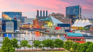 A waterfront cityscape with modern buildings, a bridge, and boats. - Holiday Inn Baltimore BWI Airport by IHG (Linthicum Heights)