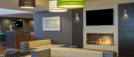 Una sala de estar moderna con un sofá, una chimenea y un televisor montado en la pared.