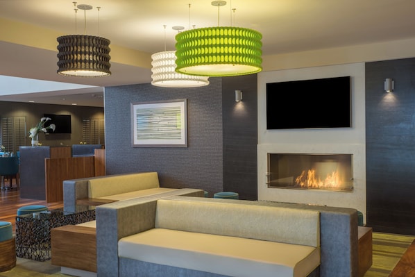 A modern living room with a sofa, a fireplace, and a television mounted on the wall. - Holiday Inn Baltimore BWI Airport by IHG (Linthicum Heights)