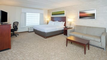 Una habitación de hotel con cama, escritorio, sillón, sofá y mesita de centro.