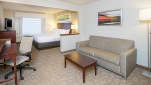 Ein Hotelzimmer mit Bett, einer Couch, einem Schreibtisch und einem Fernseher.