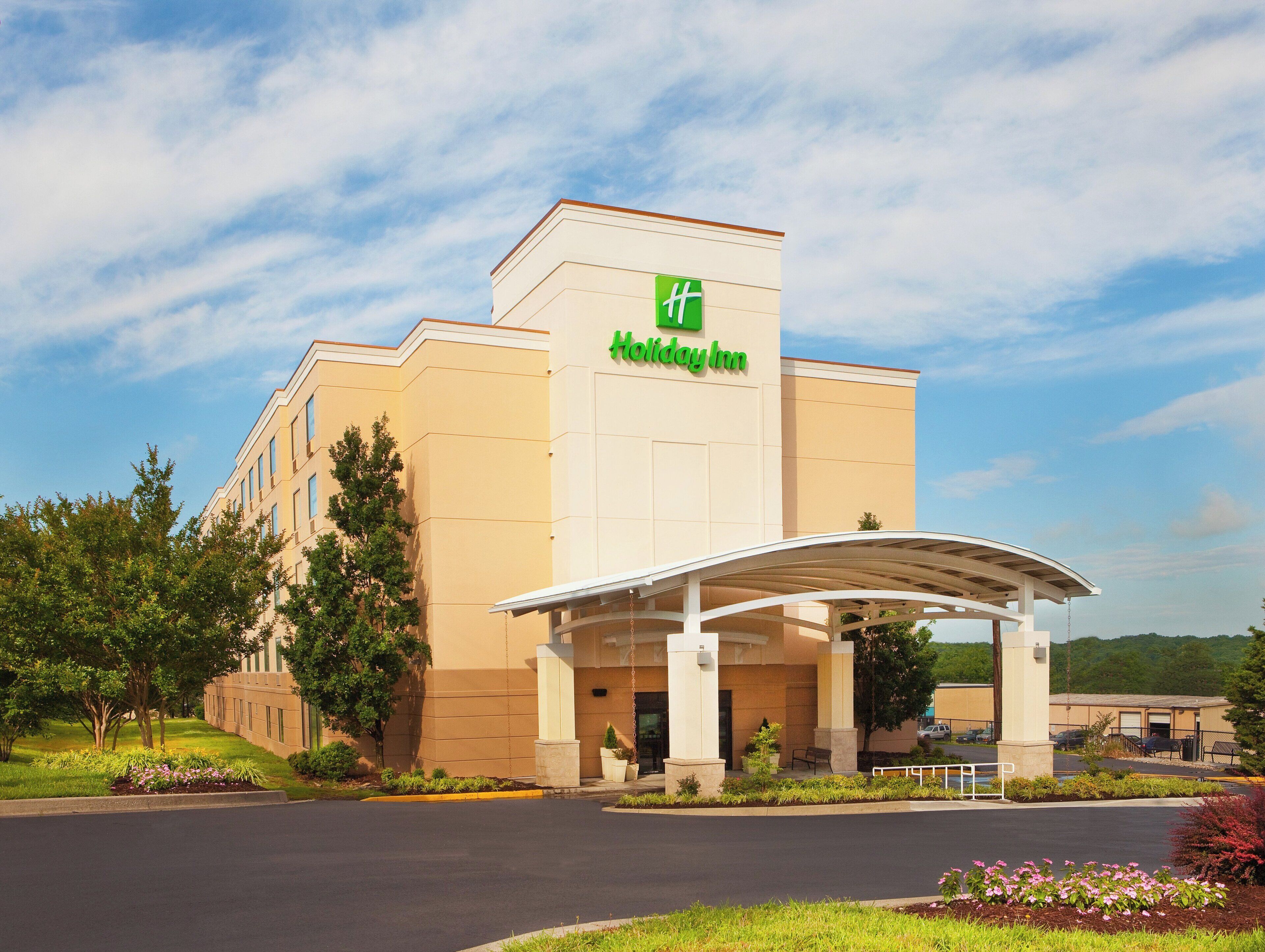 A Holiday Inn hotel with a covered entrance and a parking lot.