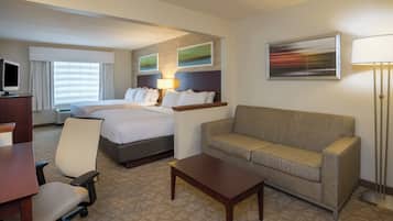 A hotel room with a bed, a sofa, a desk, a chair, and a TV.