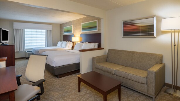 A hotel room with a bed, a sofa, a desk, a chair, and a TV. - Holiday Inn Baltimore BWI Airport by IHG (Linthicum Heights)