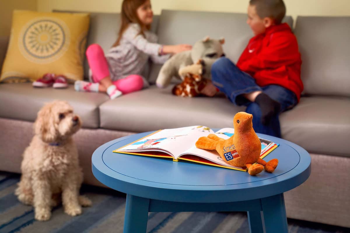 A living room with a round blue table, a sofa, and a dog.