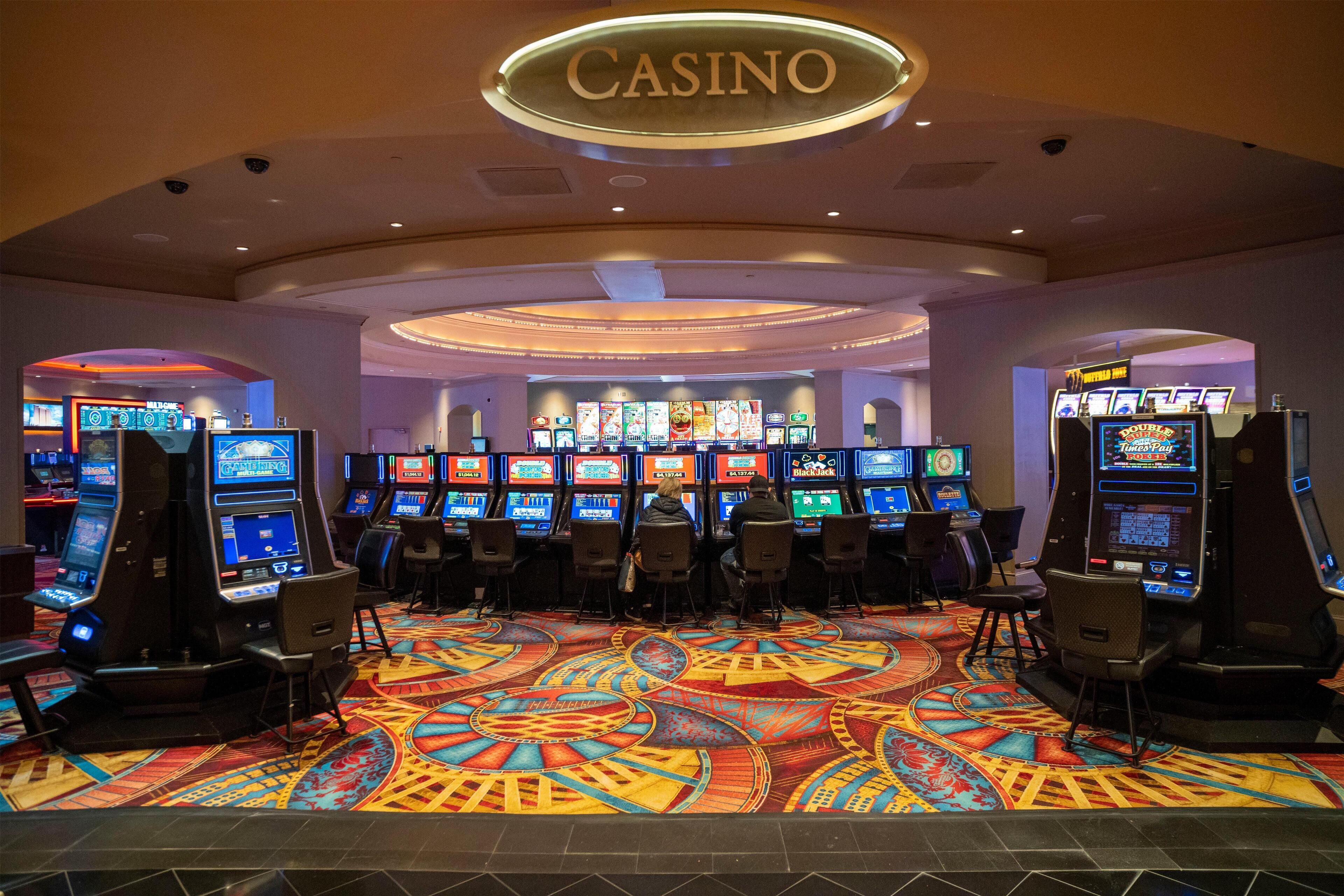A casino with multiple slot machines and a colorful carpet.