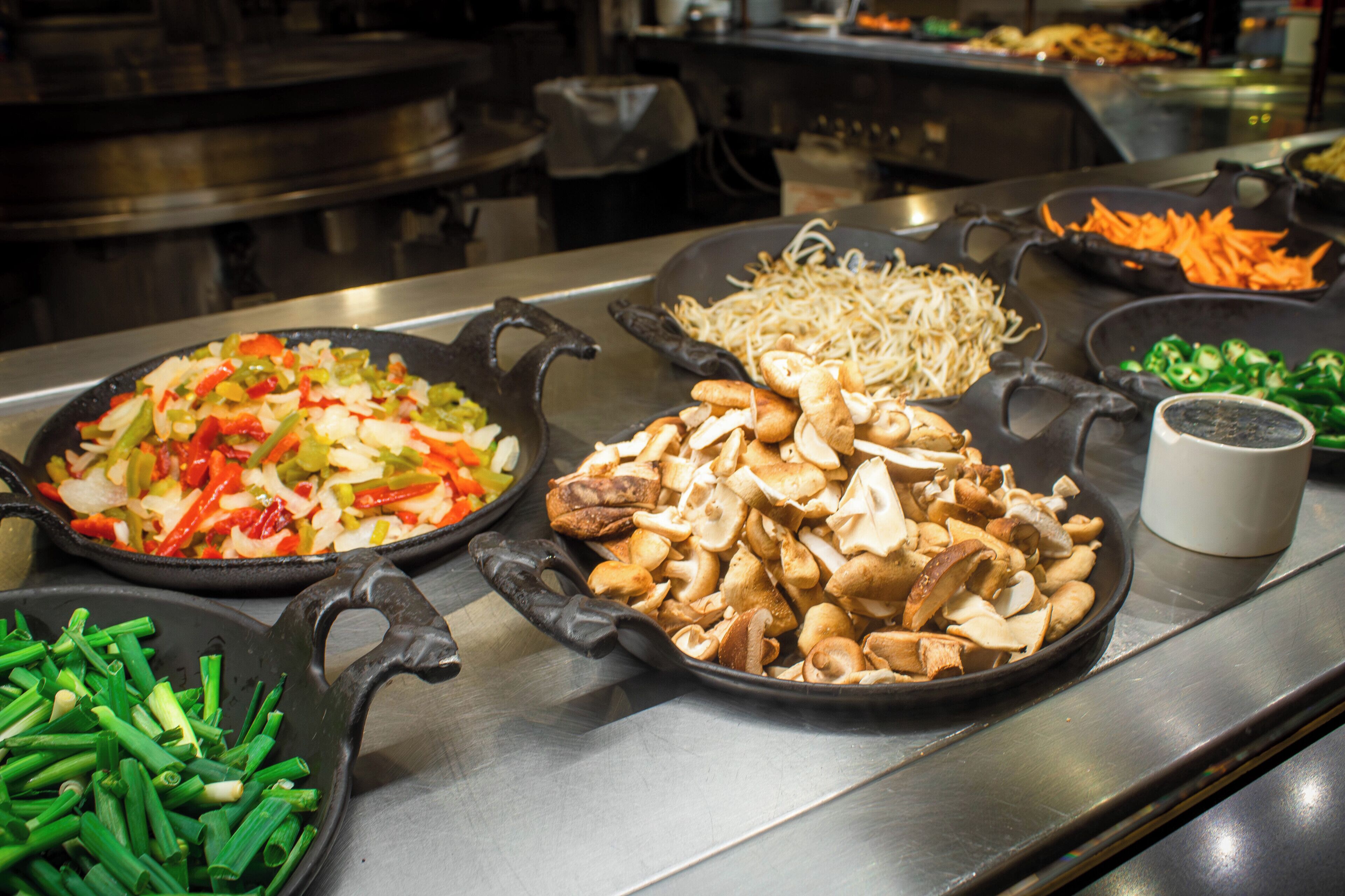 A kitchen counter with various food items including vegetables and mushrooms.