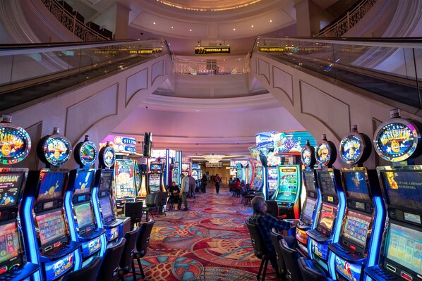 A casino area with multiple slot machines, escalators, and a carpeted floor. - Gold Strike Casino Resort (Robinsonville)