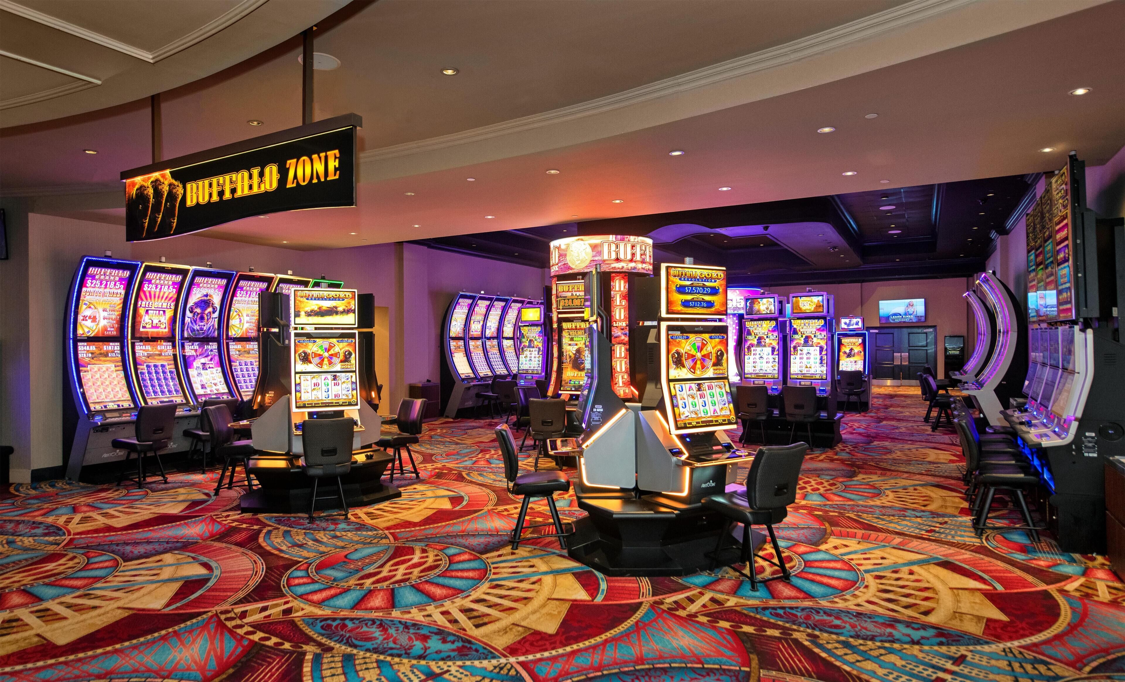 A casino area with multiple slot machines, a sign indicating the 'Buffalo Zone', and a carpeted floor with a geometric pattern.