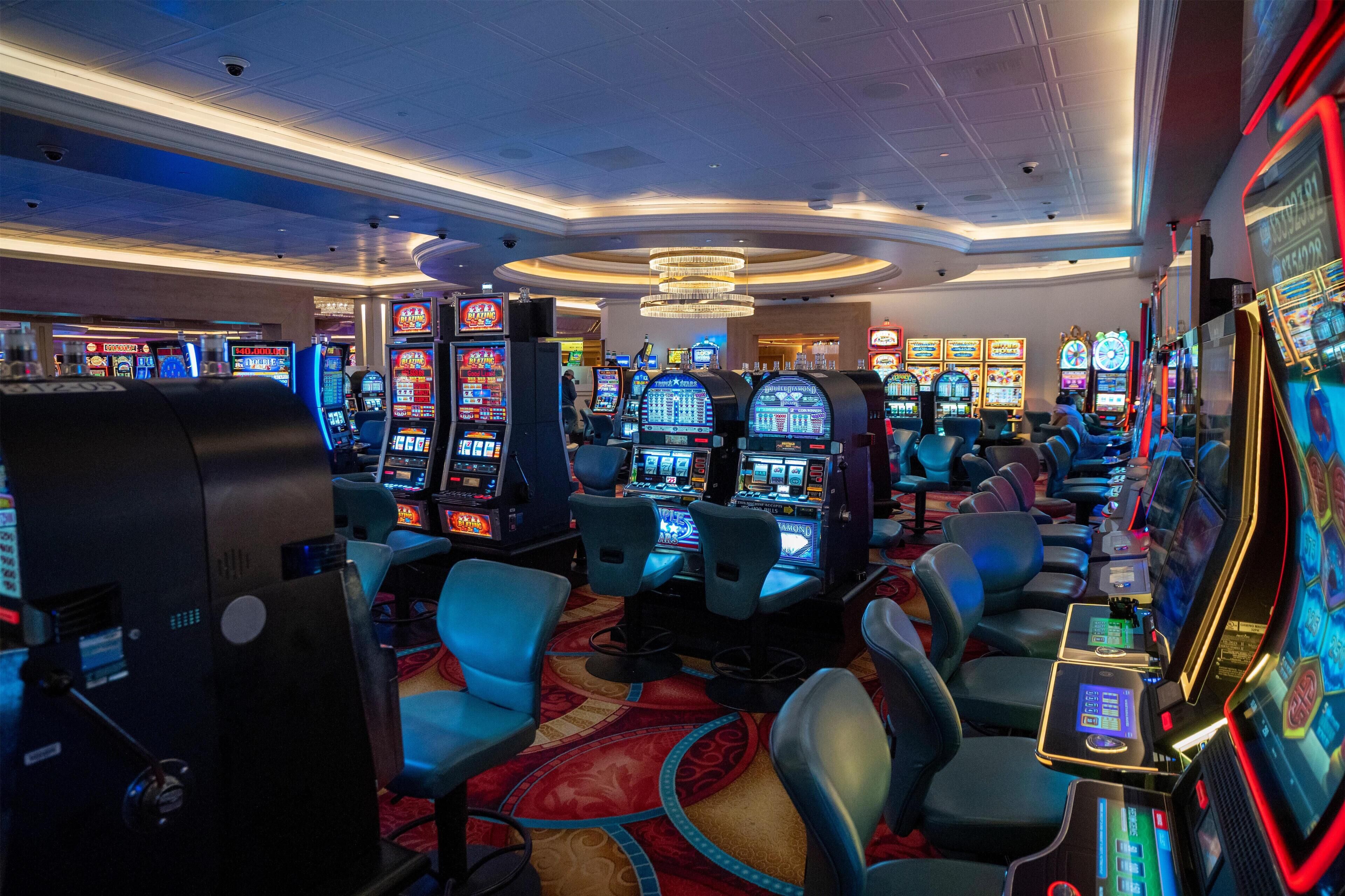 A casino with multiple slot machines, comfortable seating, and a chandelier.
