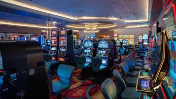 A casino with multiple slot machines, comfortable seating, and a chandelier.