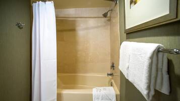 Un baño con una bañera, cortina de ducha, toallero con una toalla y un cuadro en la pared.