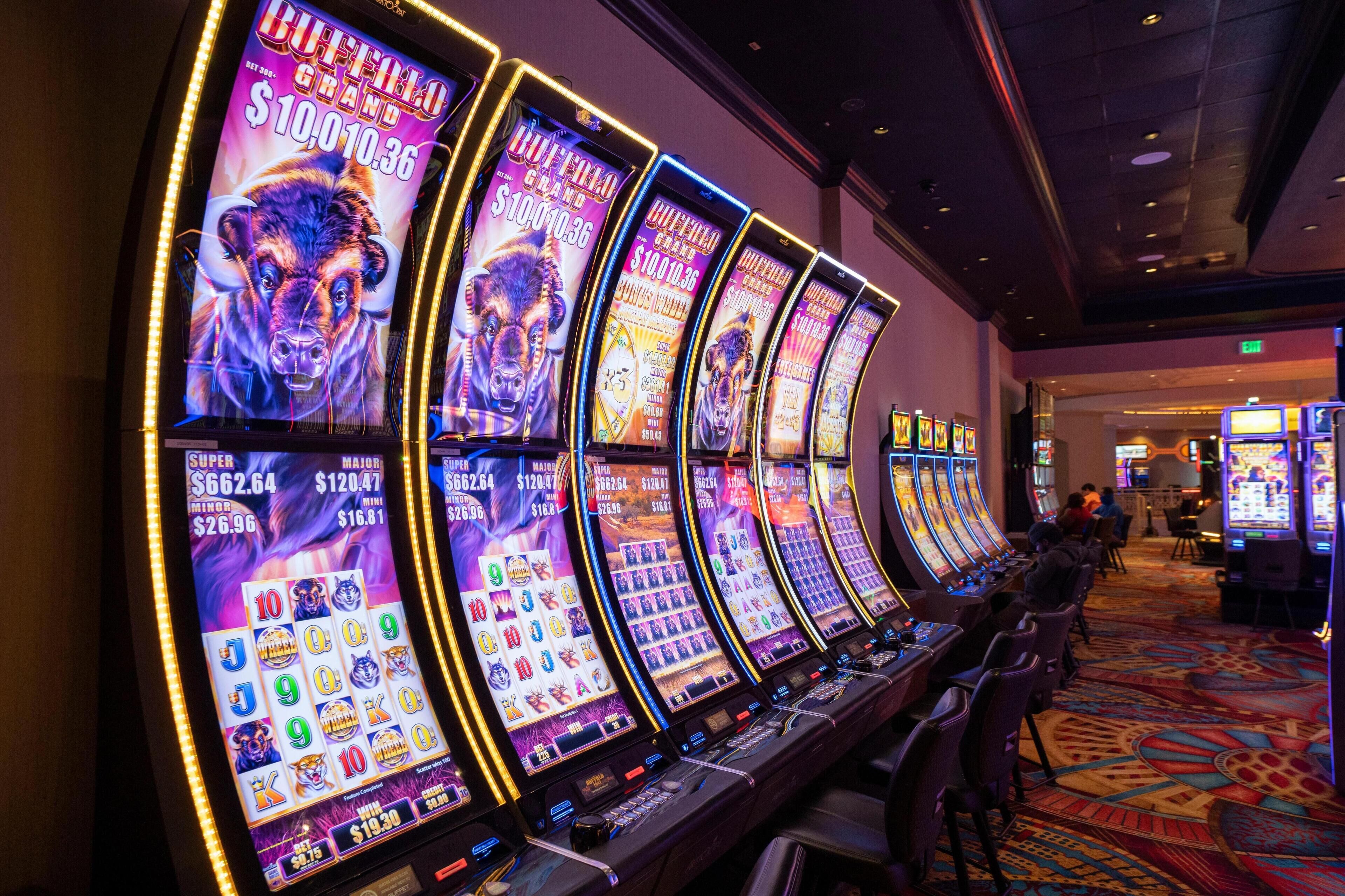 Una hilera de máquinas tragamonedas con pantallas iluminadas en un casino.