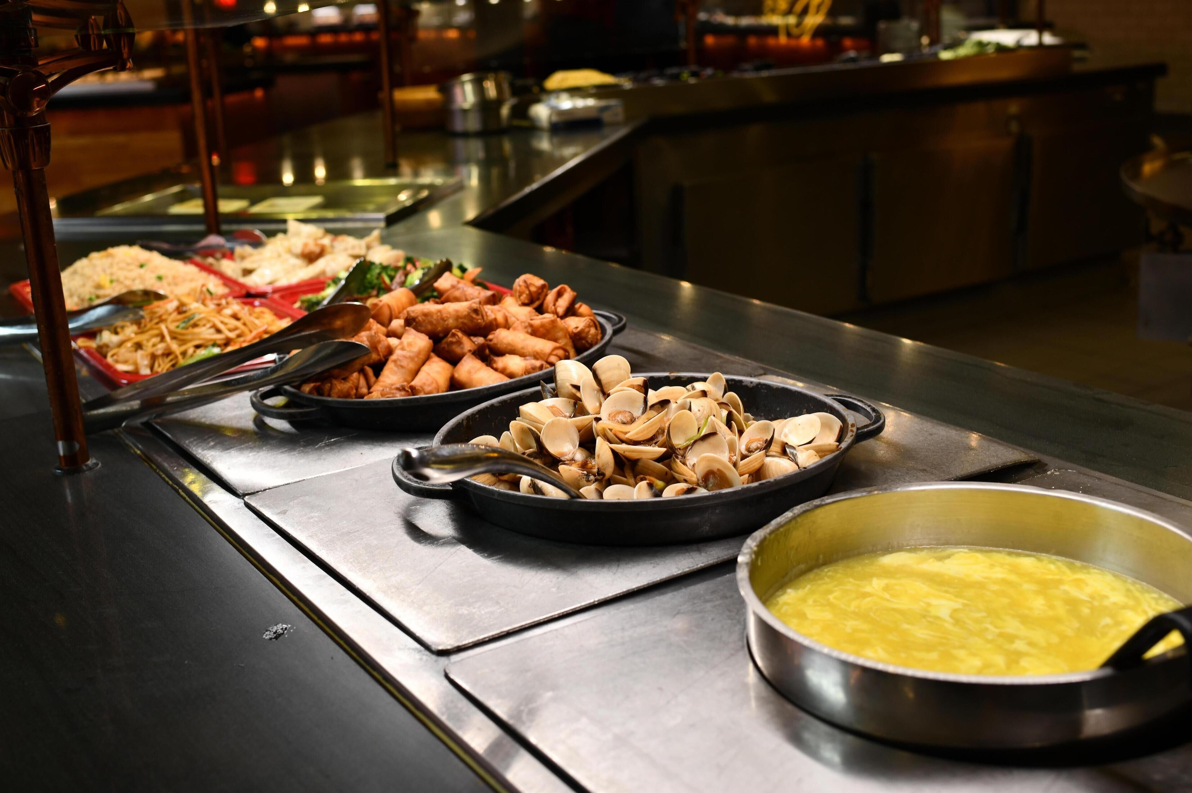 A buffet with various dishes, including fried items and a pot of soup.