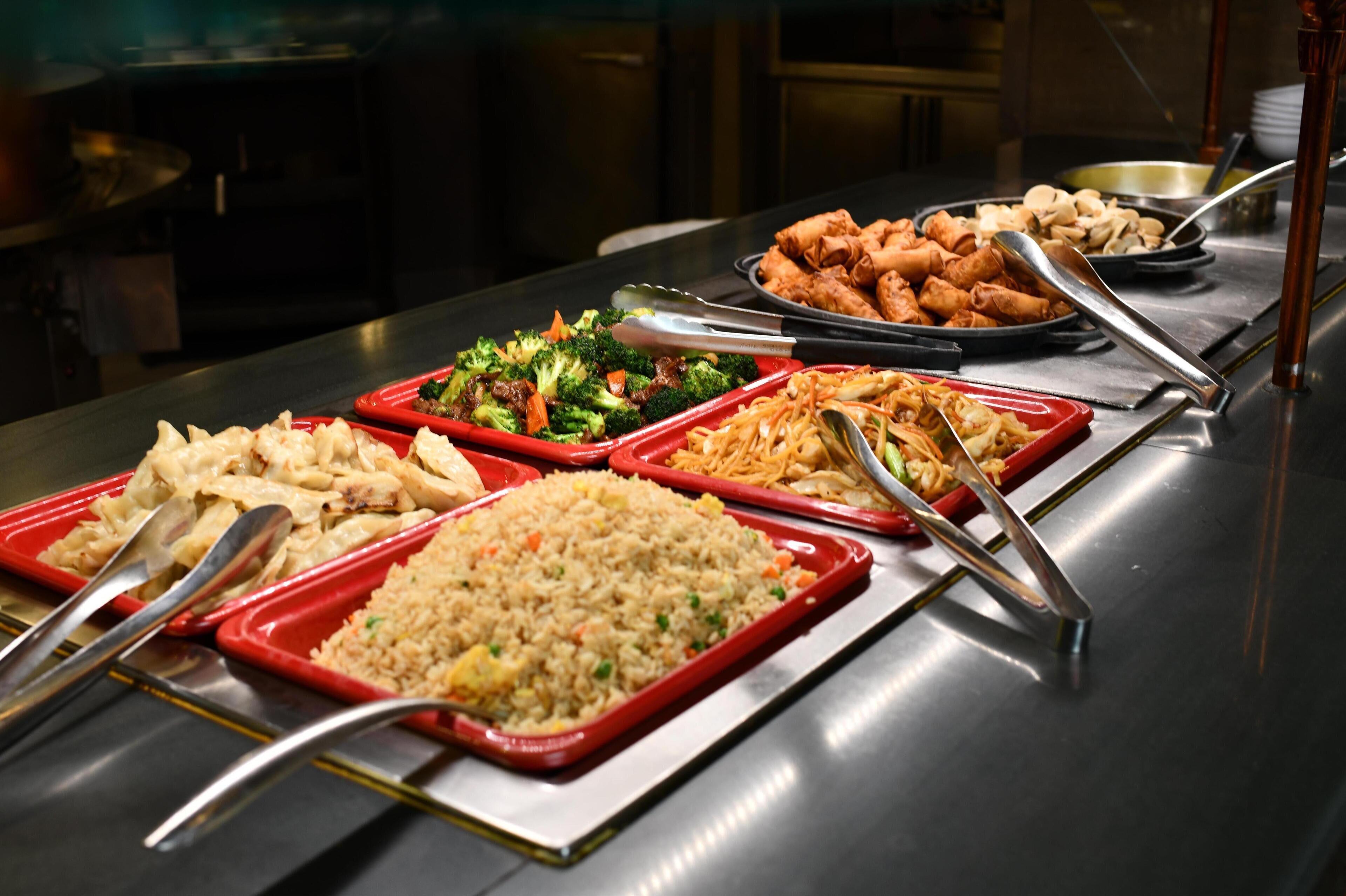 A buffet with various dishes including fried rice, vegetables, and spring rolls.