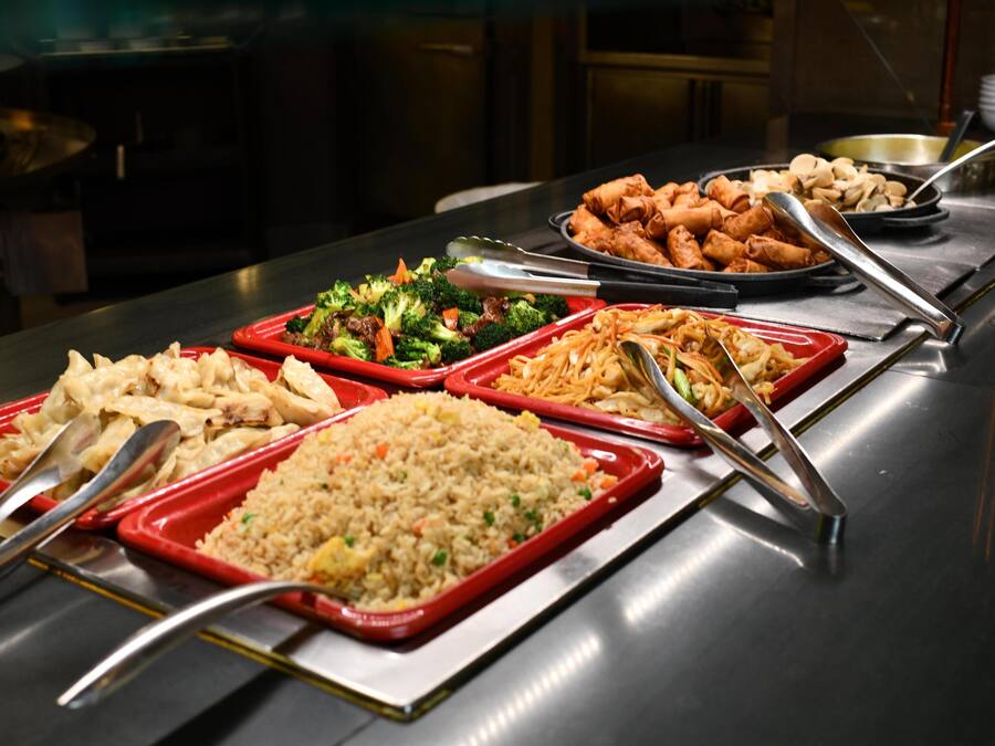 A buffet with various dishes including fried rice, vegetables, and spring rolls.
