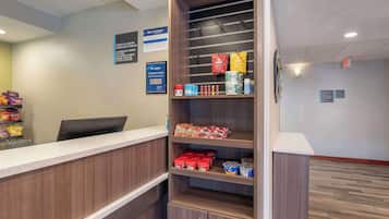 A reception area with a counter, shelves stocked with snacks, and a computer.
