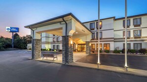 A hotel entrance with a covered waiting area, stone pillars, and a clear view of the entrance doors.