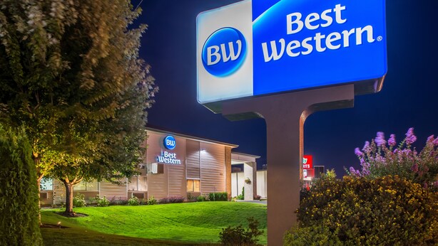 Schild eines Best Western Hotels mit Logo, ein gut beleuchtetes Gebäude und ein gepflegter Rasen.