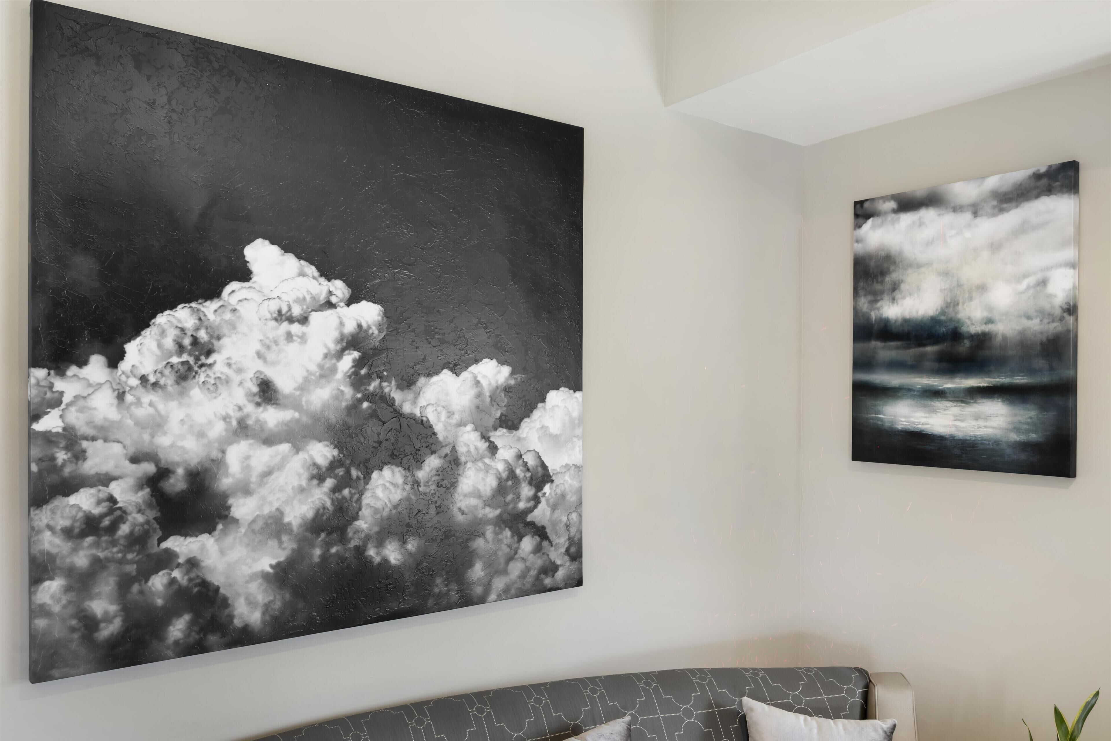 Ein Wohnzimmer mit einem großen, abstrakten Gemälde von Wolken an der Wand.