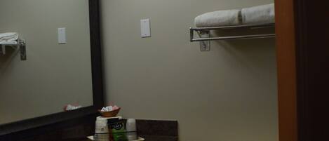 A bathroom with a sink, mirror, toilet, and towel rack.