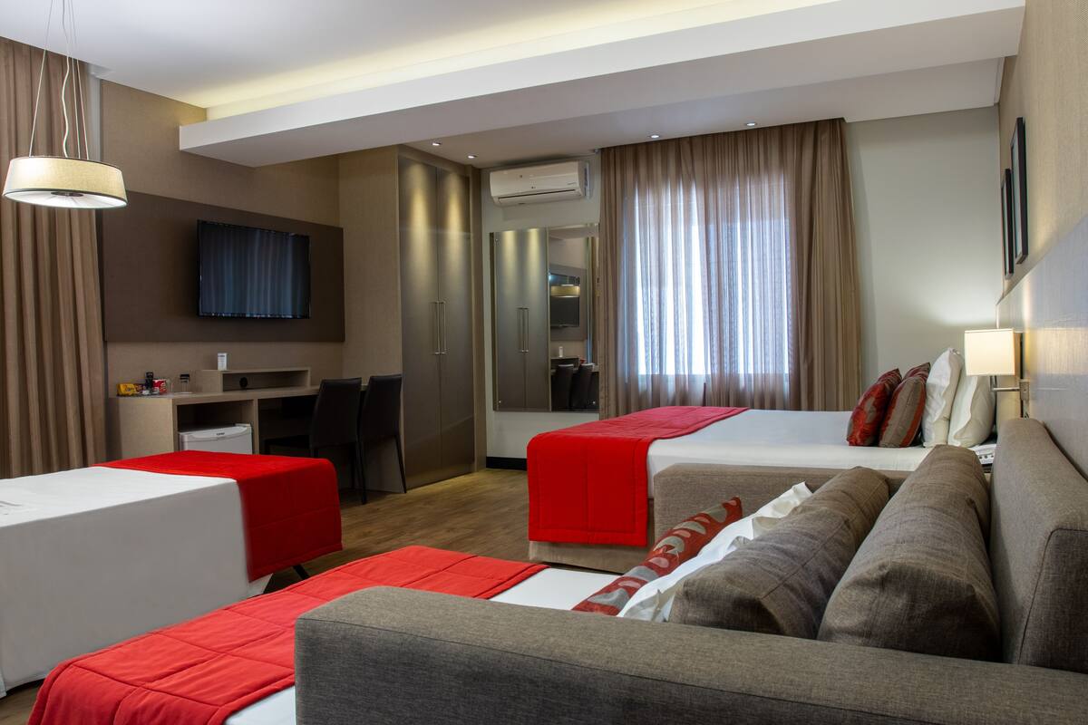 Ein Hotelzimmer mit zwei Betten, einem Schreibtisch, einem Fernseher und einer Minibar.
