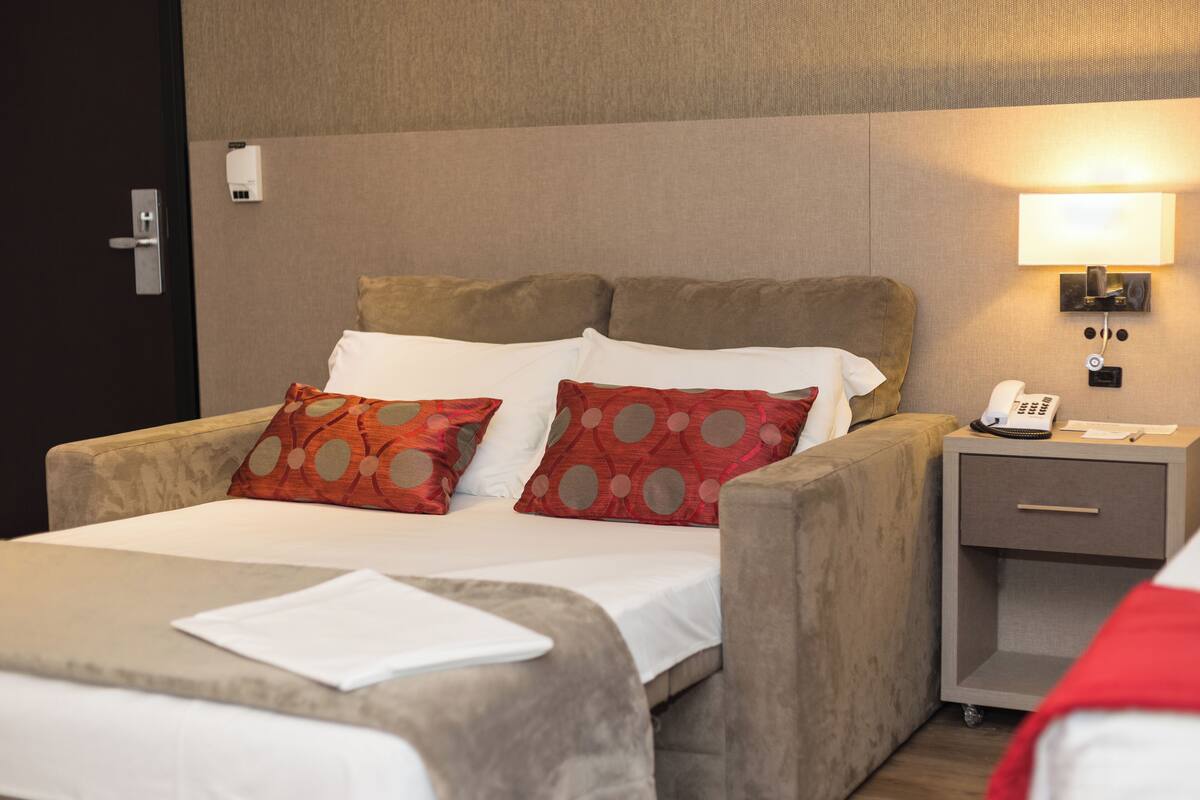 Ein Hotelzimmer mit einem Bett, einem Nachttisch und einer Wandlampe.