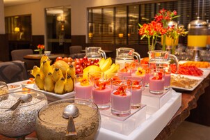 Un buffet con frutta assortita, centrifughe e granola.