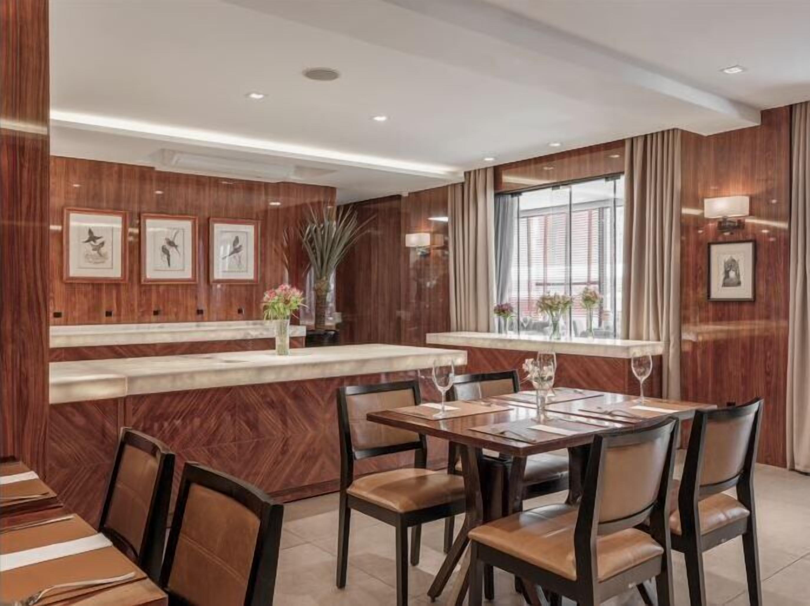 A hotel dining area with wooden paneling, a marble counter, and framed artwork on the walls.