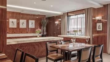 A hotel dining area with wooden paneling, a marble counter, and framed artwork on the walls.