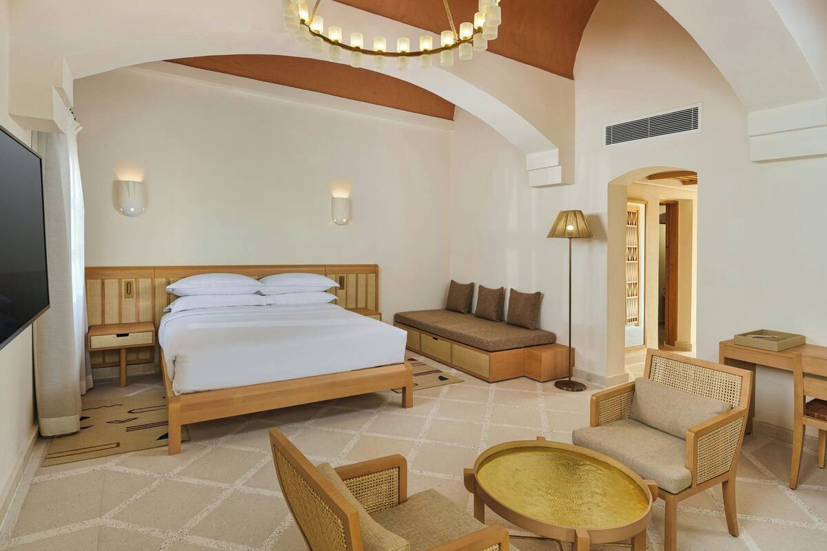 A spacious bedroom with a large bed, a sofa, and a dining area.