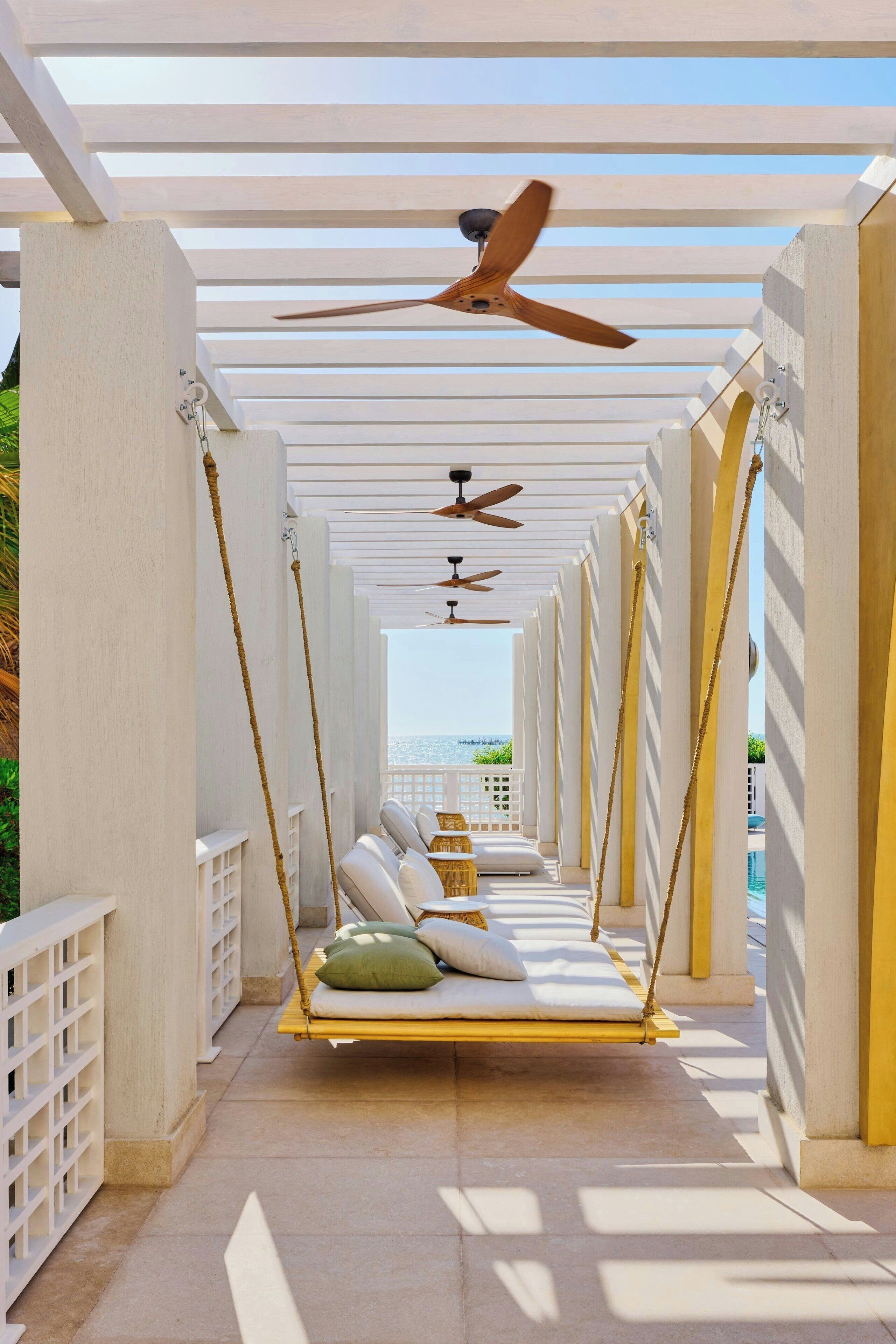 A covered outdoor area with swings and a view of the sea.