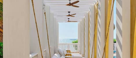 A covered outdoor area with swings and a view of the sea.