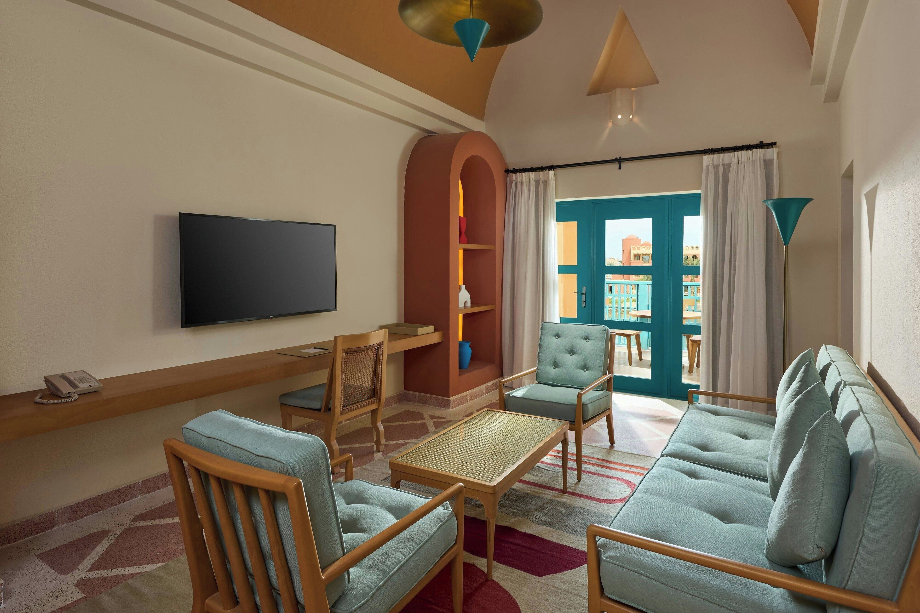 A living room with a flat-screen TV, wooden furniture, a sofa, and a view of the outside.