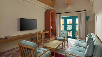 A living room with a flat-screen TV, wooden furniture, a sofa, and a view of the outside.