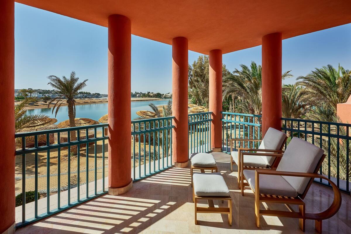 A balcony with a view of a pool and palm trees.