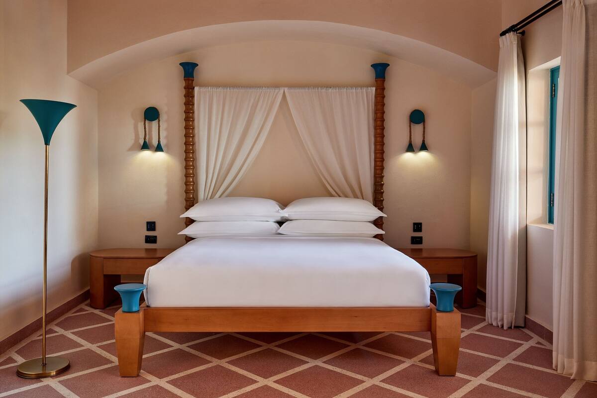 A neatly arranged bedroom with a wooden bed, two bedside tables, a floor lamp, and a window with curtains.