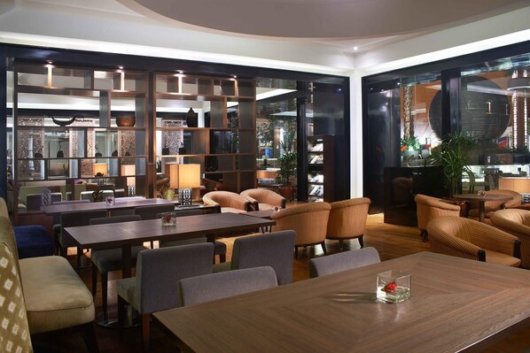 A modern interior with a dining area, sofas, and a bookshelf. - Gran Melia Jakarta (Jakarta)