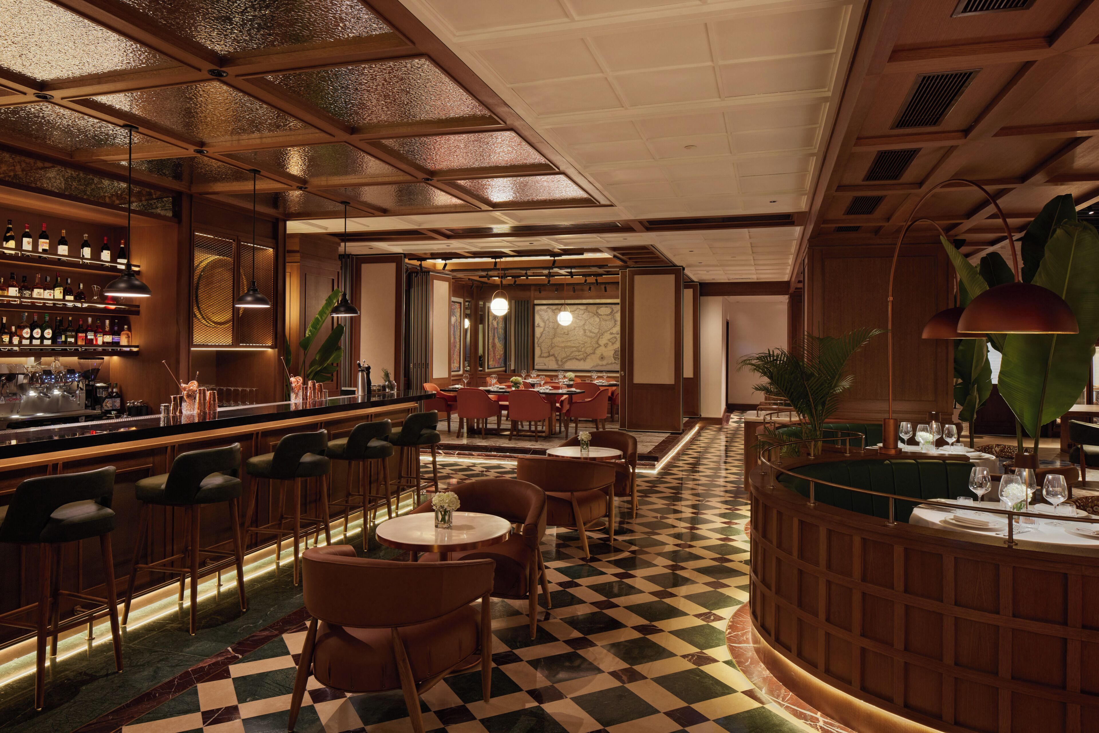 Zona de bar con taburetes, una barra con botellas y una sección de comedor con mesas y sillas.