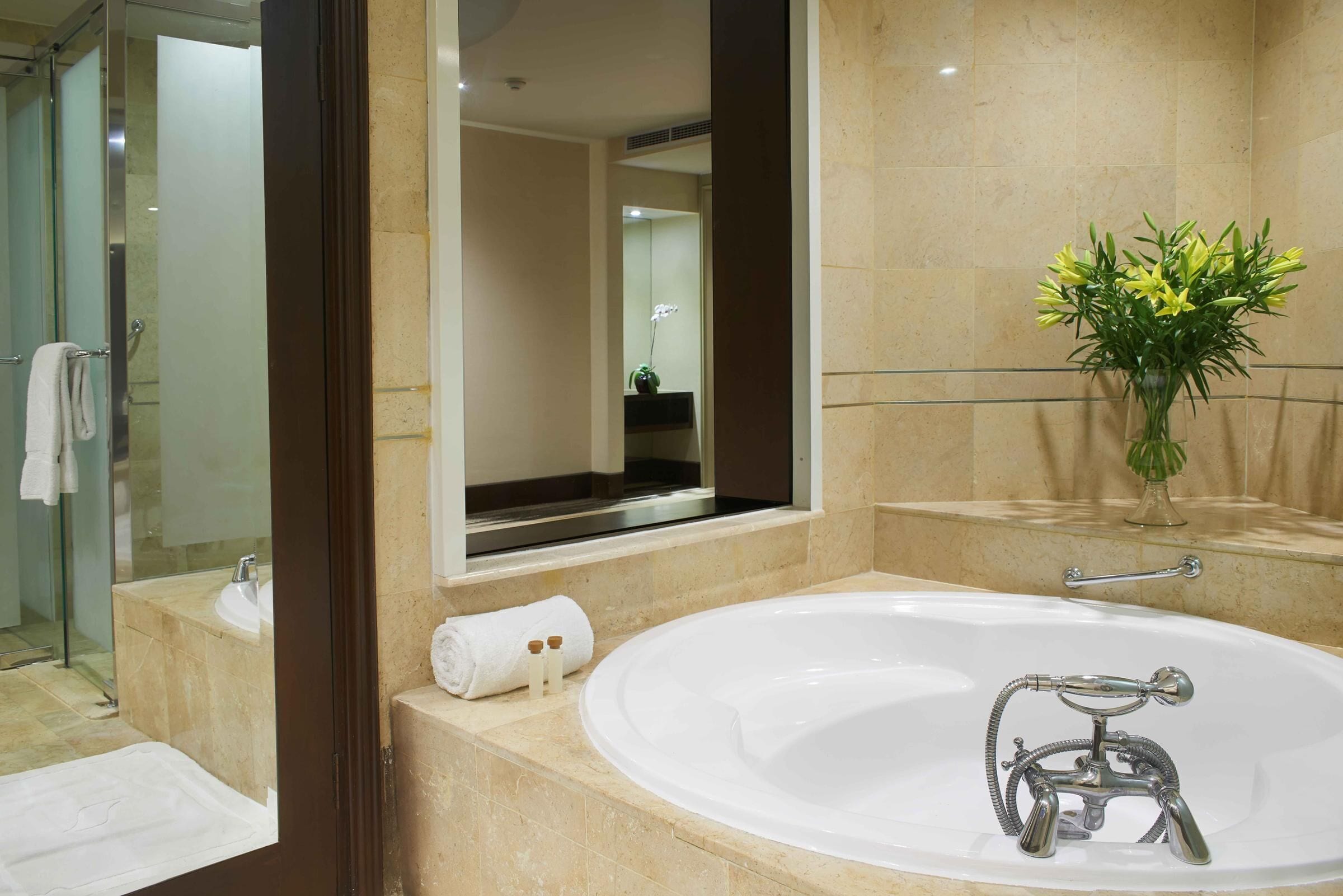Un baño moderno con una bañera grande, una cabina de ducha de vidrio y un espejo que refleja la habitación.