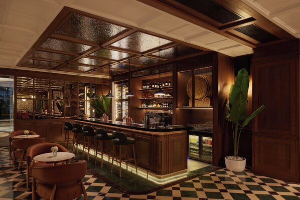 A bar area with a checkered floor, wooden bar counter, and bar stools. - Gran Melia Jakarta (Jakarta)