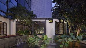 A modern building with a water feature and lush greenery. - Gran Melia Jakarta (Jakarta)